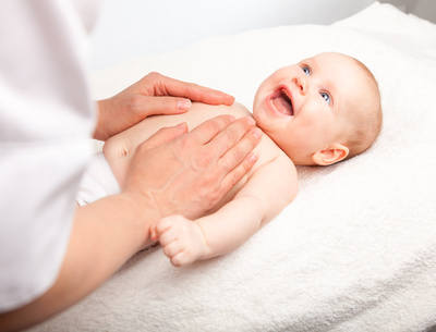 Three month baby girl is receiving chest massage from a female massage therapist